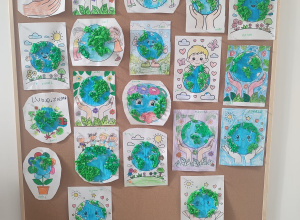 Na zdjęciu widoczne są prace plastyczne wykonane przez dzieci, przedstawiające planetę Ziemię. Kolorowe ilustracje ukazują Ziemię w kreatywny sposób, podkreślając zaangażowanie dzieci.