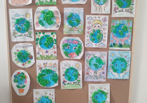 Na zdjęciu widoczne są prace plastyczne wykonane przez dzieci, przedstawiające planetę Ziemię. Kolorowe ilustracje ukazują Ziemię w kreatywny sposób, podkreślając zaangażowanie dzieci w tematykę przyrodniczą i ekologiczną.
