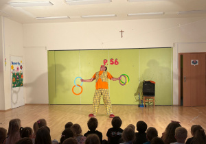 Klaun prezentuje sztuczki z hula-hop podczas występu cyrkowego w przedszkolu.