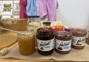 Na zdjęciu widać różne rodzaje miodów w słoikach. Produkty mają różne kolory i konsystencje, co pokazuje ich naturalne pochodzenie i różnorodność.